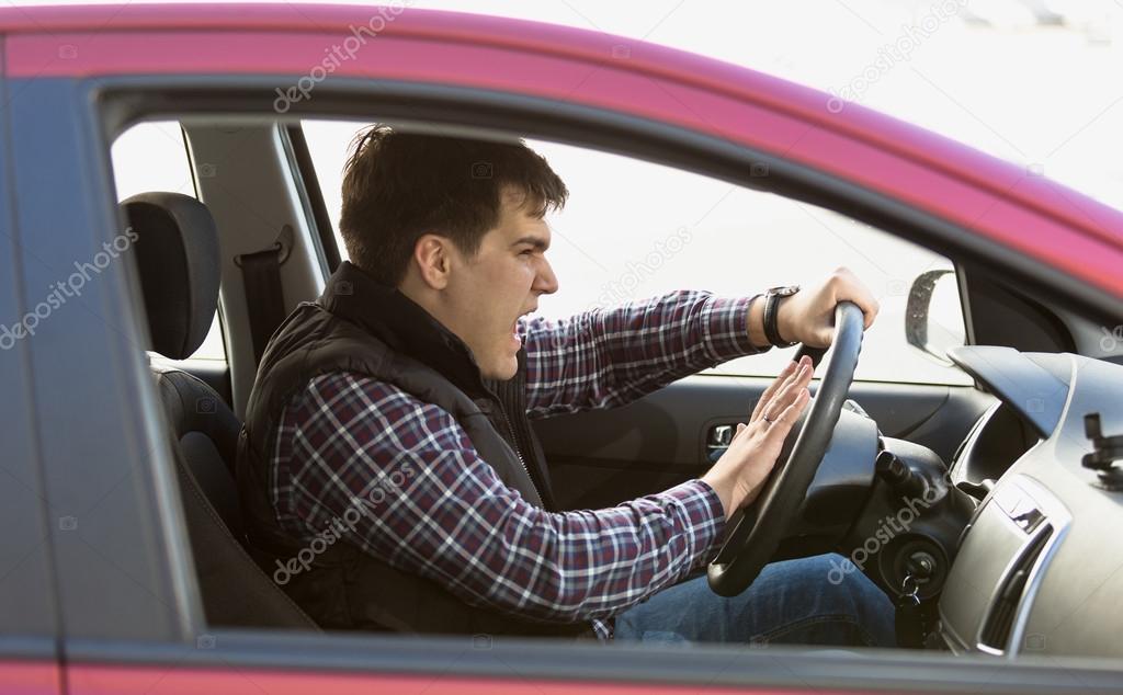 portrait of aggressive male driver honking in traffic jam