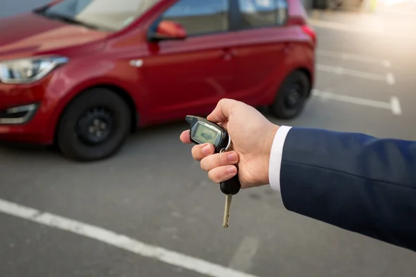 Fecho do homem pressionando o botão no sistema de alarme remoto do carro — Fotografia de Stock