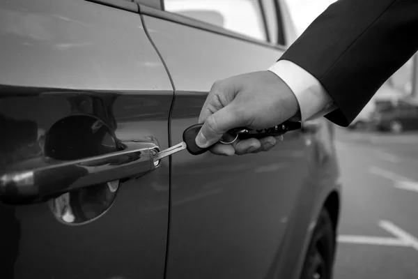 Černá a bílá closeup člověka vložení klíče od auta v díře — Stock fotografie