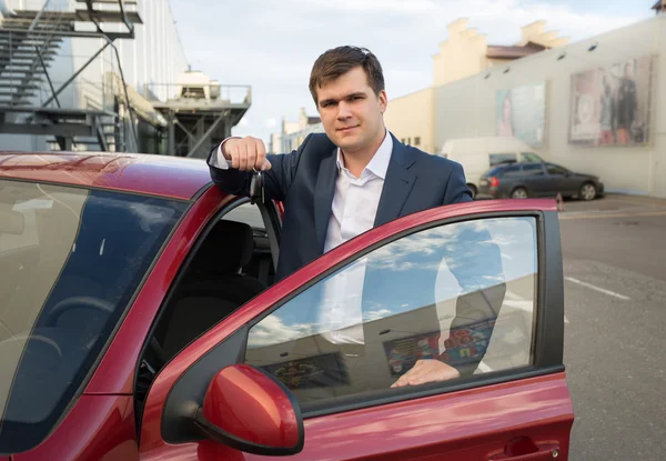 Hombre feliz posando con coche nuevo y mostrando las llaves —  Fotos de Stock