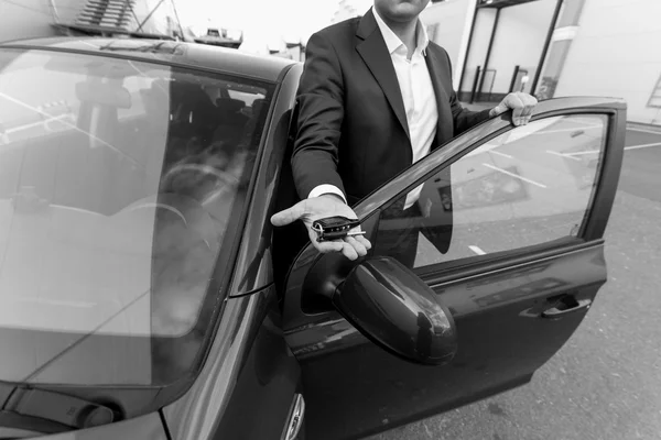 Black and white closeup of car sales manager holding key on hand — Stock Photo, Image