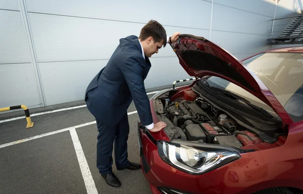 Empresário estressado olhando sob o capô do carro — Fotografia de Stock