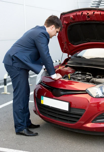 Uomo in giacca e cravatta cercando sotto cofano auto — Foto Stock