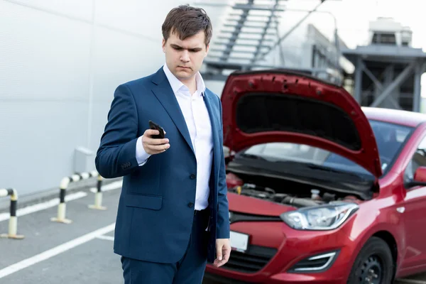 Hombre de negocios de pie en el coche roto y utilizando el teléfono — Foto de Stock