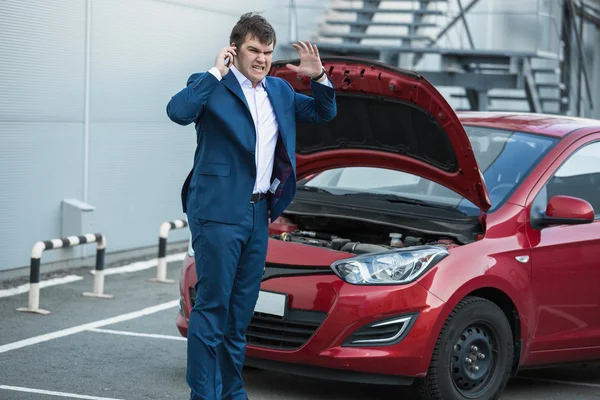 Zakenman permanent naast gebroken auto en belt in dienst — Stockfoto