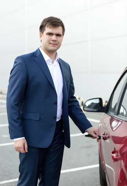 Handsome young businessman opening car door — Stock Photo, Image