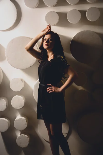 Brunette woman posing at hard light against fancy white wall — Stock Photo, Image