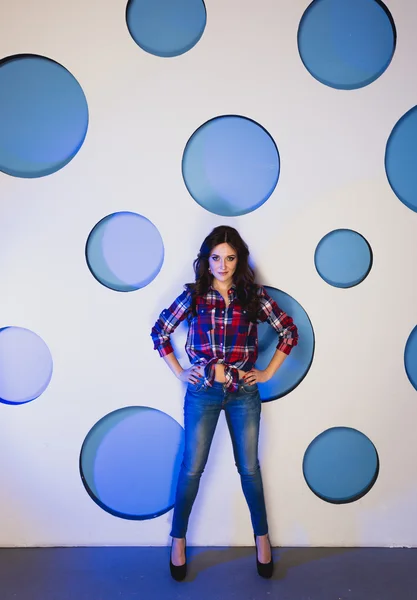 Donna magra in jeans posa sullo sfondo con cerchi blu — Foto Stock