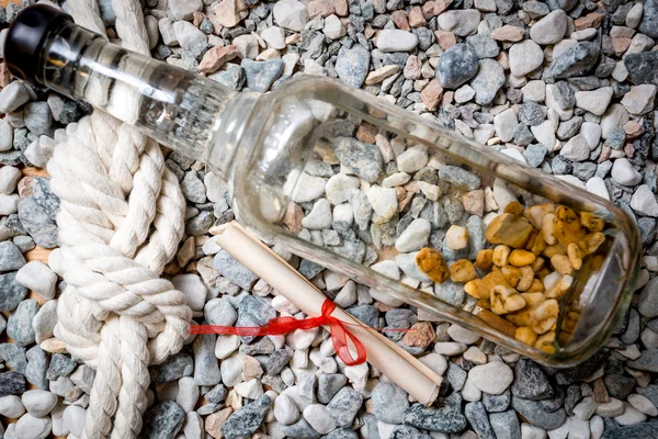 Nahaufnahme von Brief, Flasche und Meeresknoten, die auf Kieselsteinen liegen — Stockfoto