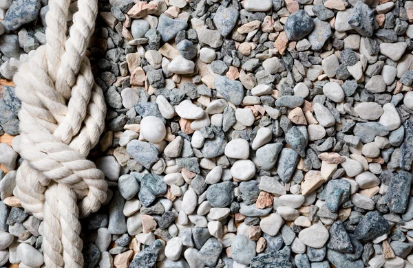 Closeup of marine knot lying on seashore covered by pebbles — Stock Photo, Image