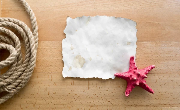 Starfish lying on blank piece of paper over wooden boards — Stock Photo, Image