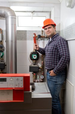 plumber installing heating system at boiler room clipart