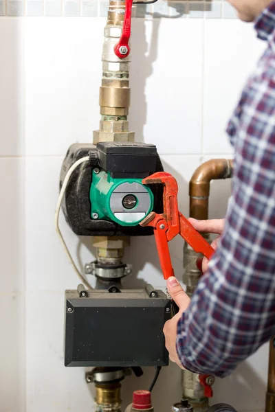 Closeup of plumber repairing heating system with red pliers — Stock Photo, Image