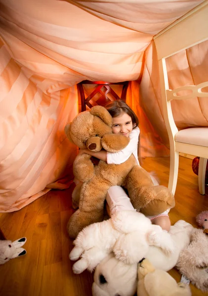 Девушка в пижаме играет с плюшевым плюшевым мишкой в спальне — стоковое фото