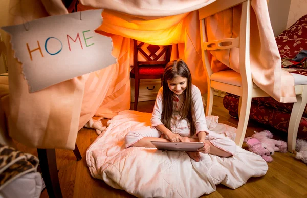 Söt flicka sitter på golvet i sovrummet och använder digital tablet — Stockfoto
