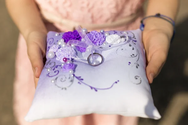 Primer plano de niña sosteniendo cojín con anillos de boda —  Fotos de Stock