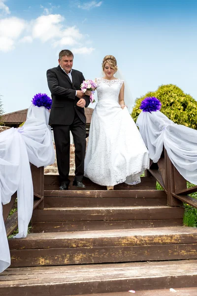 Pai levando noiva feliz ao altar de casamento descendo as escadas — Fotografia de Stock
