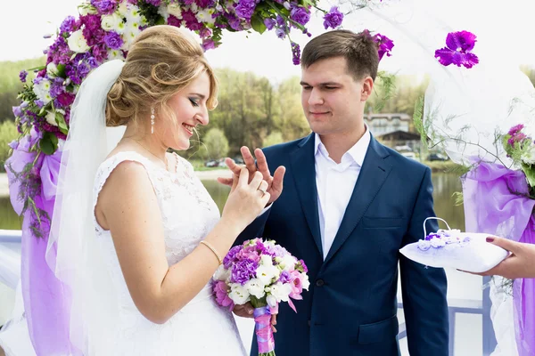 Bride putting golden ring on grooms hand at wedding ceremony — Stock Photo, Image