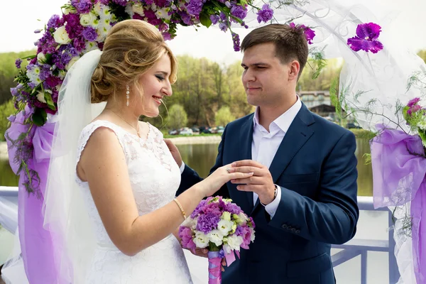 Guapo novio sonriente poniendo anillo en la mano de las novias —  Fotos de Stock