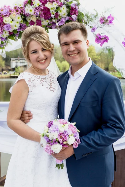 花の装飾的なアーチの下でポーズをとって aughing ちょうど結婚されていたカップル — ストック写真