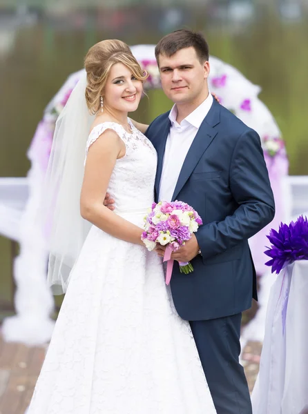 Retrato de novia feliz y novio abrazándose contra el arco —  Fotos de Stock