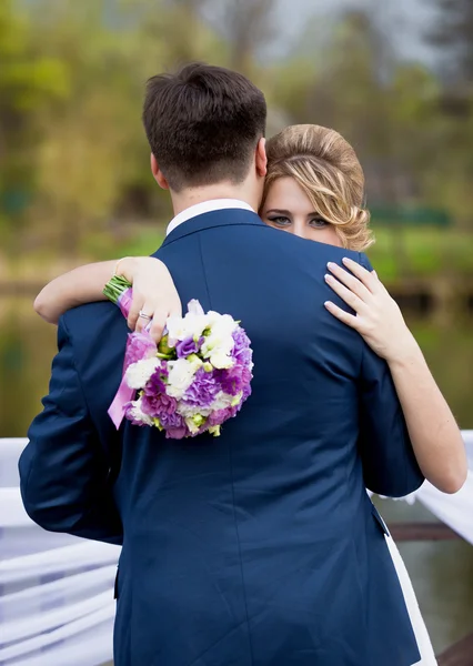 Close-up van elegante blonde bruid over bruidegoms schouder kijken — Stockfoto