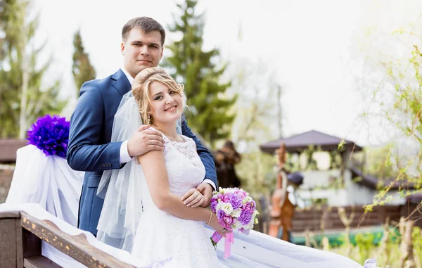 Портрет красивого жениха, обнимающего улыбающуюся невесту в парке — стоковое фото