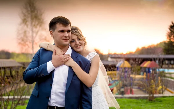 Sposa felice abbracciare lo sposo da indietro al bel tramonto — Foto Stock