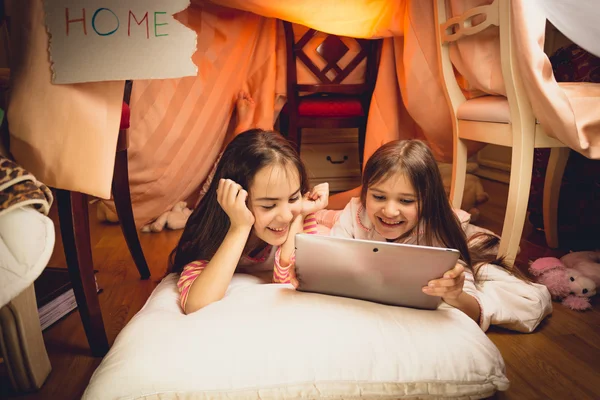 Happy girls using digital tablet in house made of blankets Stock Photo