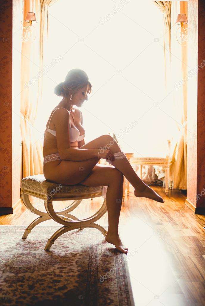 Toned photo against window of elegant woman sitting on chair