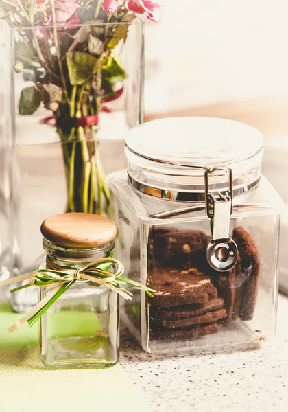 Foto tonificada de galletas de chocolate en frasco de vidrio en la mesa de la cocina — Foto de Stock