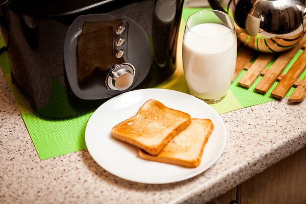 Closeup of baked toasts lying on white dish with glass of milk
