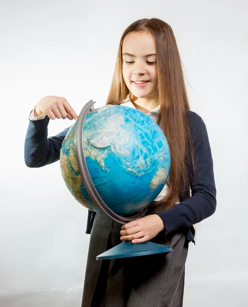 Carino sorridente ragazza che punta al globo terrestre contro backgrou bianco — Foto Stock