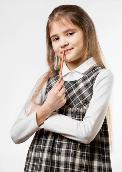 Nachdenkliches Schulmädchen kaut Bleistift vor weißem Hintergrund — Stockfoto