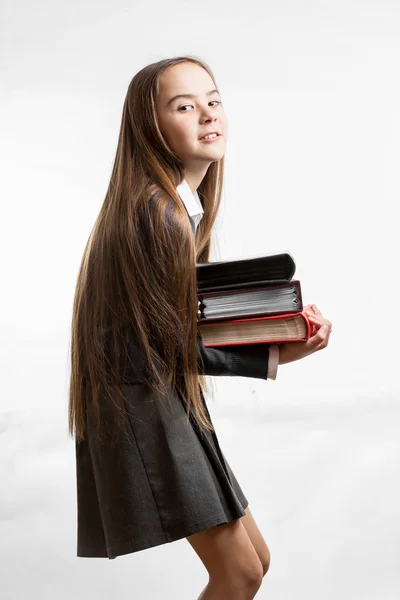Iskoláslány egyenruhában szállító nehéz verem a könyvek — Stock Fotó