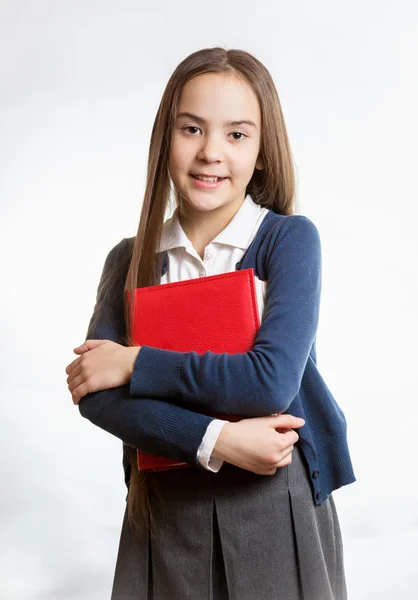 Lächelndes Schulmädchen posiert mit rotem Buch vor isoliertem Hintergrund — Stockfoto