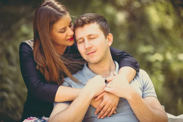 Retrato tonificado de una hermosa mujer abrazando novio en el parque — Foto de Stock