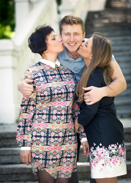 Duas mulheres beijando bonito sorrindo homem em bochechas — Fotografia de Stock