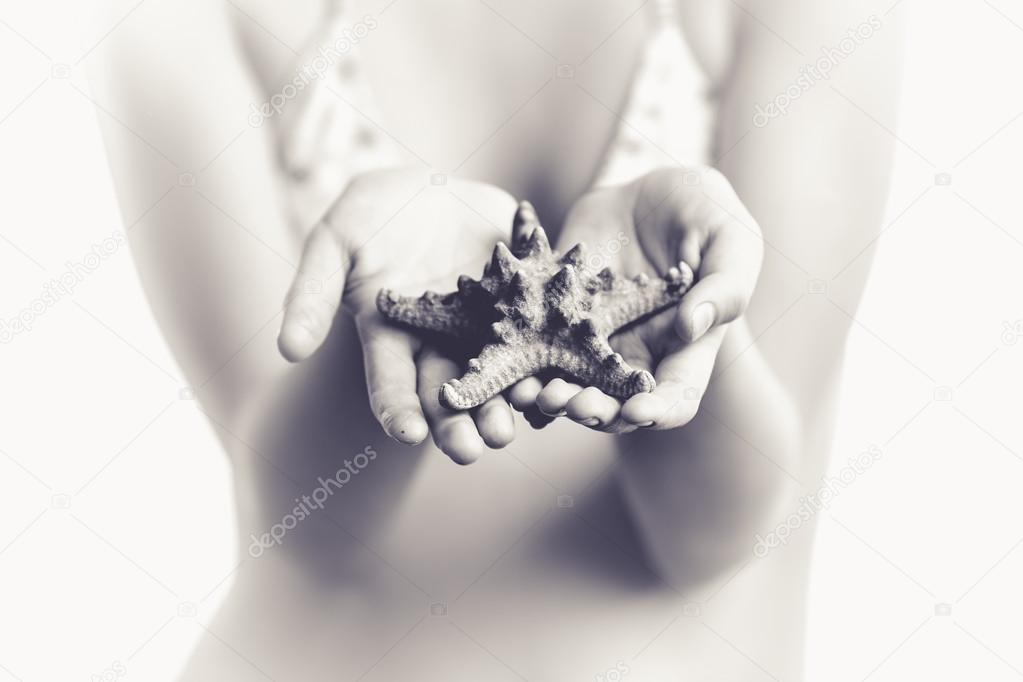 toned photo of girl holding big starfish in hands
