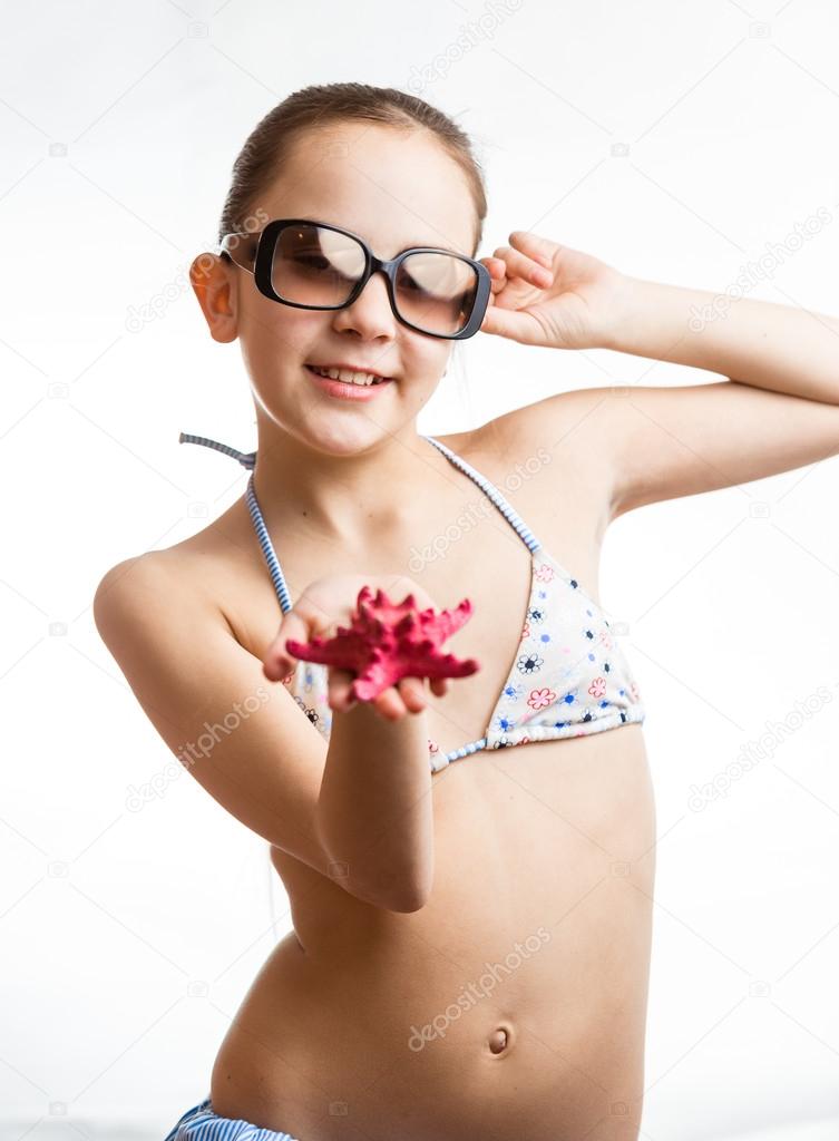 cute girl in sunglasses showing red starfish on hand