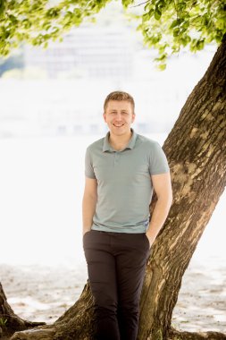 genç adam riverbank, ağacın altında poz