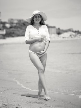 Deniz sahilde poz şapkalı şirin hamile kadının fotoğrafını tonda