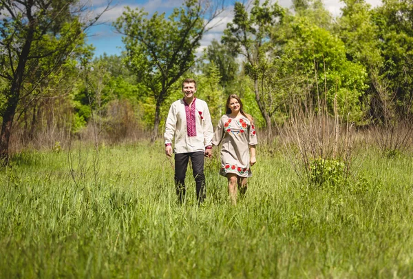 Casal em roupas eslavas tradicionais andando no prado — Fotografia de Stock