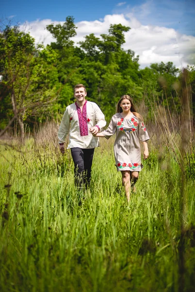 Traditional ukrainian couple holding hands and walking at field — Stock Photo, Image