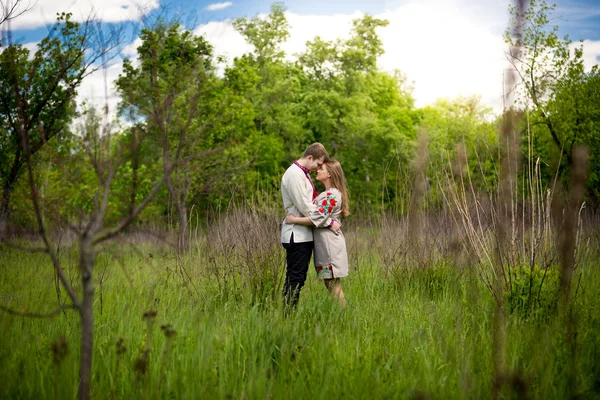 Casal em roupas tradicionais ucranianas abraçando na floresta — Fotografia de Stock