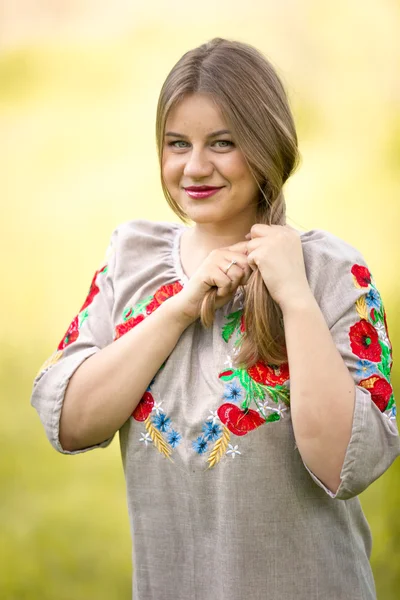 Linda mujer en ropa tradicional ucraniana haciendo trenza en fiel — Foto de Stock