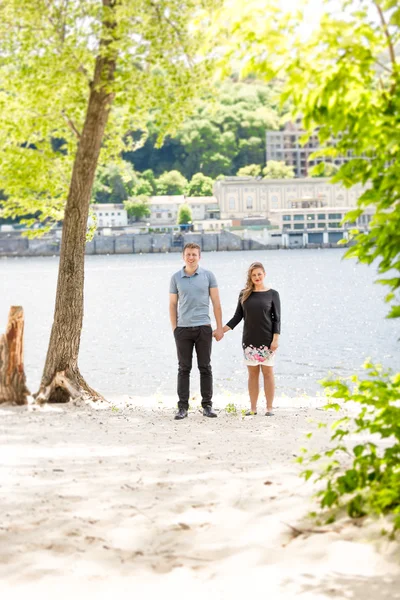 Pareja enamorada cogida de la mano bajo un gran árbol en la orilla del río —  Fotos de Stock