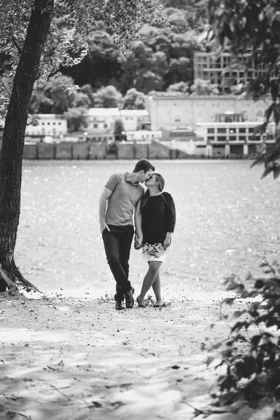 黑色和白色的年轻夫妇在河上的爱情接吻的照片 — 图库照片