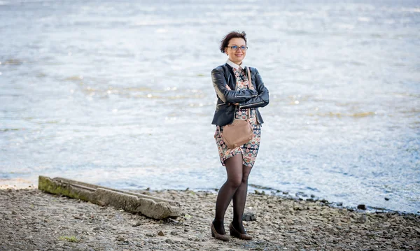 Snygg kvinna i skinnjacka poserar på flodstranden på kall dag — Stockfoto