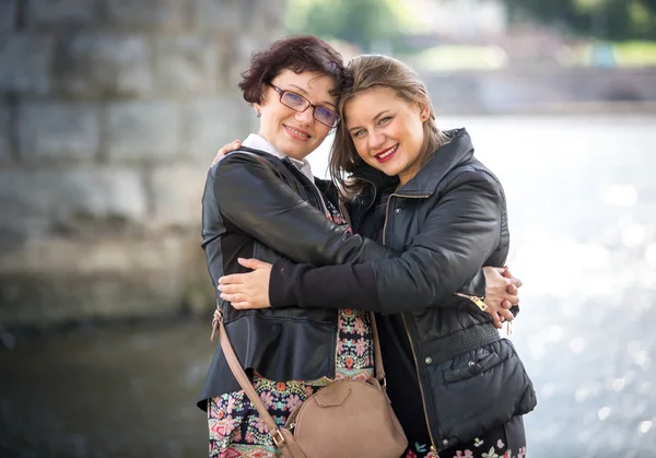 Glücklich erwachsene Tochter umarmt mit Mutter am Flussufer — Stockfoto